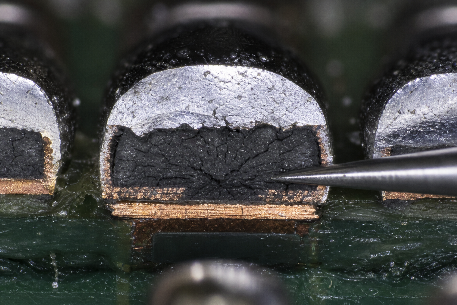 Microscope close-up of black pad syndrome corrosion on an ENIG circuit board pad.